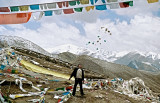 Tibet : Photo taken at a high pass on the Tibetan Plateau at about 5300mts above sea level, a mans trows praying flags in to the air.