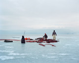 Allanngorpoq 9 : At the edge of the sea ice at around 1 a.m., hunters cut up the seals brought back by the boat after the hunt - Over the last few decades, Greenland’s society has undergone profound evolution. Thus, as the environment shifts, its people begin to embrace Western lifestyles and modes of consumption in parallel. Supermarkets, churches and cell phones are slowly making their way into Inuit culture. For the teenagers in the major towns the memories of seal hunting trips are long gone. And when they still occur in the northernmost dwellings the traditional outfits made from animal hides mix with modern fabrics, boats are used in combination with sledges.  These radical and rapid changes raise questions about society and identity, and divide public opinion in Greenland. Its people are torn between a desire to catch up with the modern world, and a feeling that they are an ice population which, like the ice itself, is slowly melting away.  “Allanngorpoq” in Greenlandic can be...