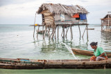 People of the Ocean : Bamasia pours water away from her boat, near her small stilt house just right offshore Sibuan island, Malaysia.