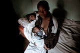 Birth is a dream - Maternity in Africa : A young girl with her first newborn, sitting on her grandmother bed